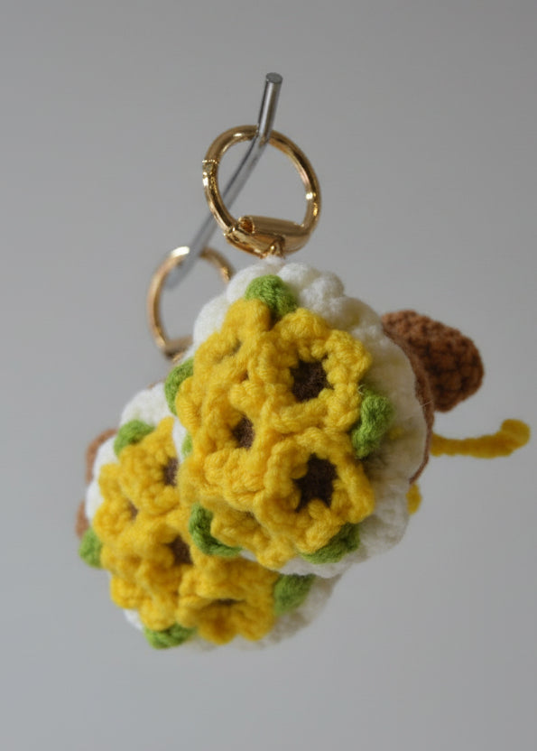 Crocheted flower keychain with gold ring on a metallic surface