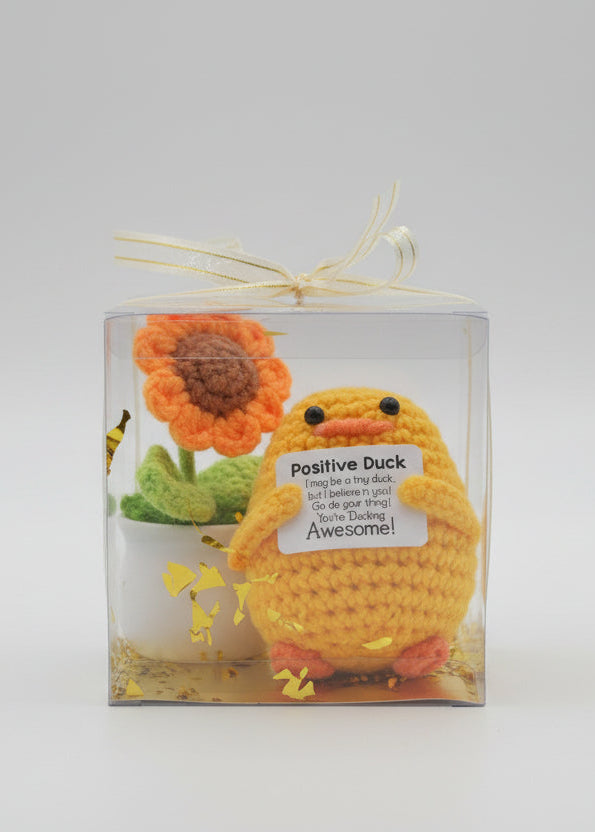 Yellow plush duck with a sunflower and a card inside a clear box.