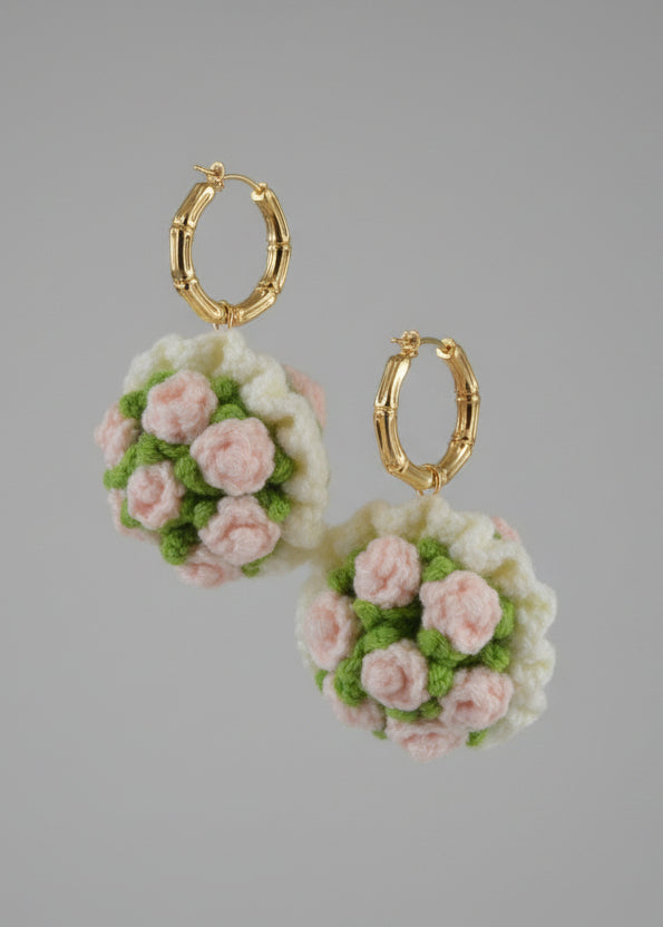 Crocheted flower keychain with pink and green flowers on a hook.