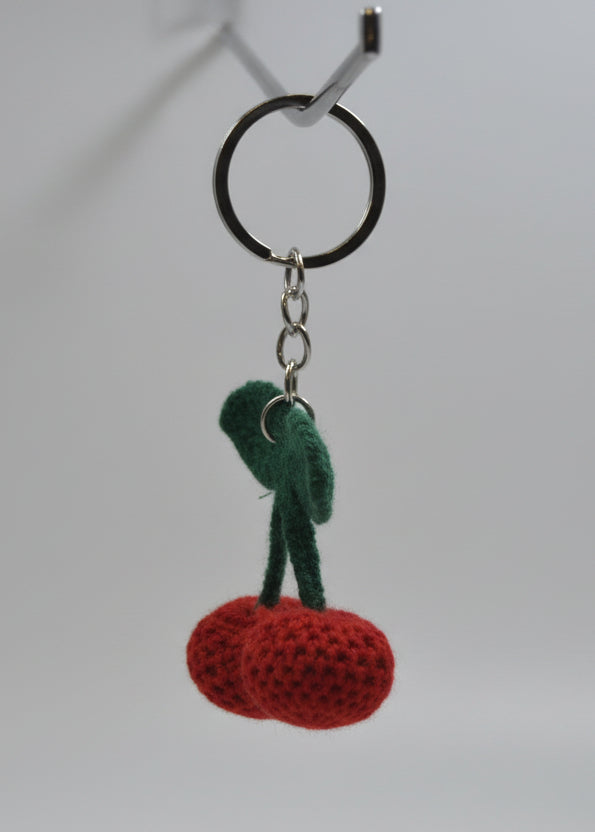 Keychain with a green and red design hanging from a metal hook on a white surface.