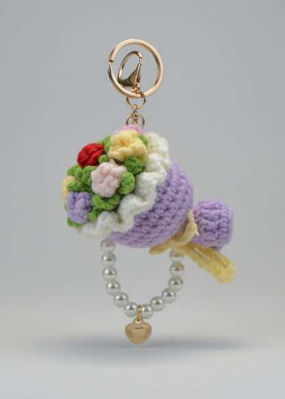 Crocheted keychain with flowers and pearls on a white surface