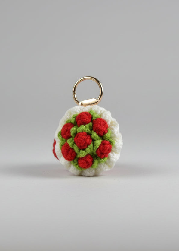 Crocheted keychain with red and green flowers on a white surface